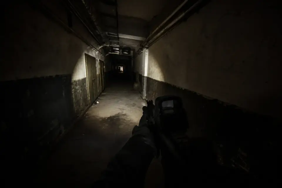 Bodycam gameplay scene in a dim corridor with flashlight cone